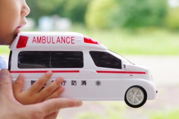 子どもが救急車の模型をもつ