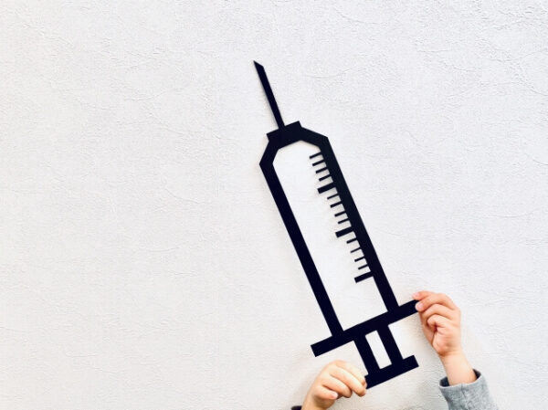 注射器の絵を持つ手